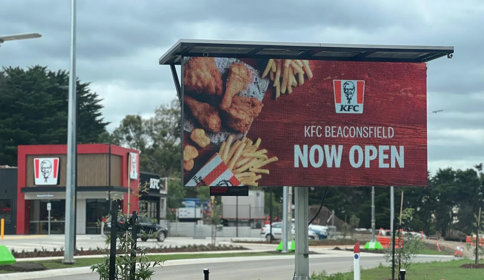 Trailer-mounted LED billboard displaying a KFC now open advertisement outside a KFC restaurant