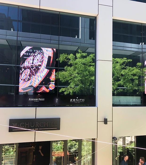 Large exterior LED advertising screen on a modern building displaying a luxury watch advertisement