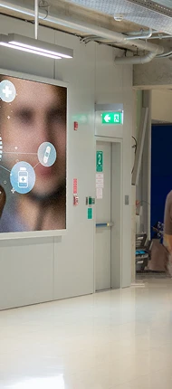 Vertical LED digital signage screen mounted in a corridor displaying information graphics