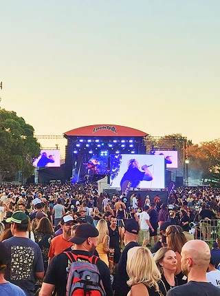 Music festival crowd at sunset in front of a stage with a large LED screen