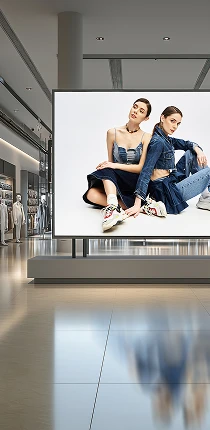 Vertical LED digital signage panel displaying a fashion advertisement in a shopping mall